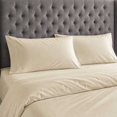 Champagne bamboo silk pillowcases and duvet cover against a grey buttoned headboard