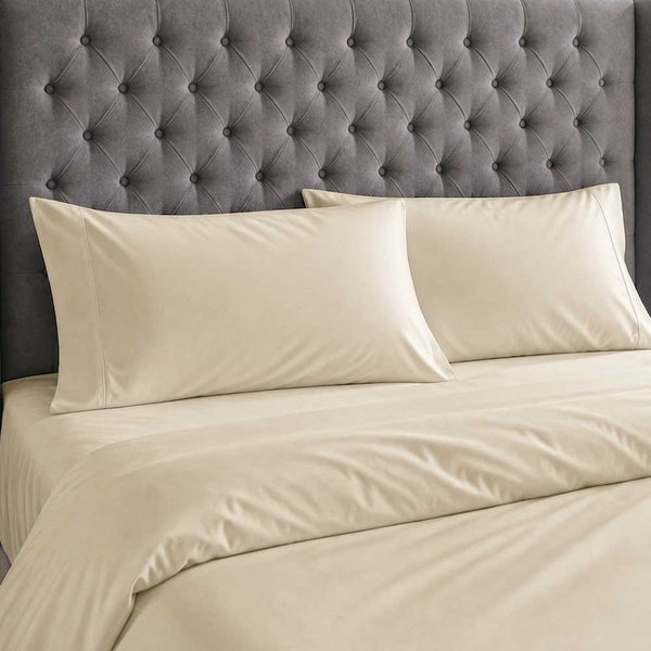 Champagne bamboo silk pillowcases and duvet cover against a grey buttoned headboard